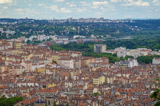 Aerial cityscape of Lyon showcasing dense historic architecture and lush greenery.