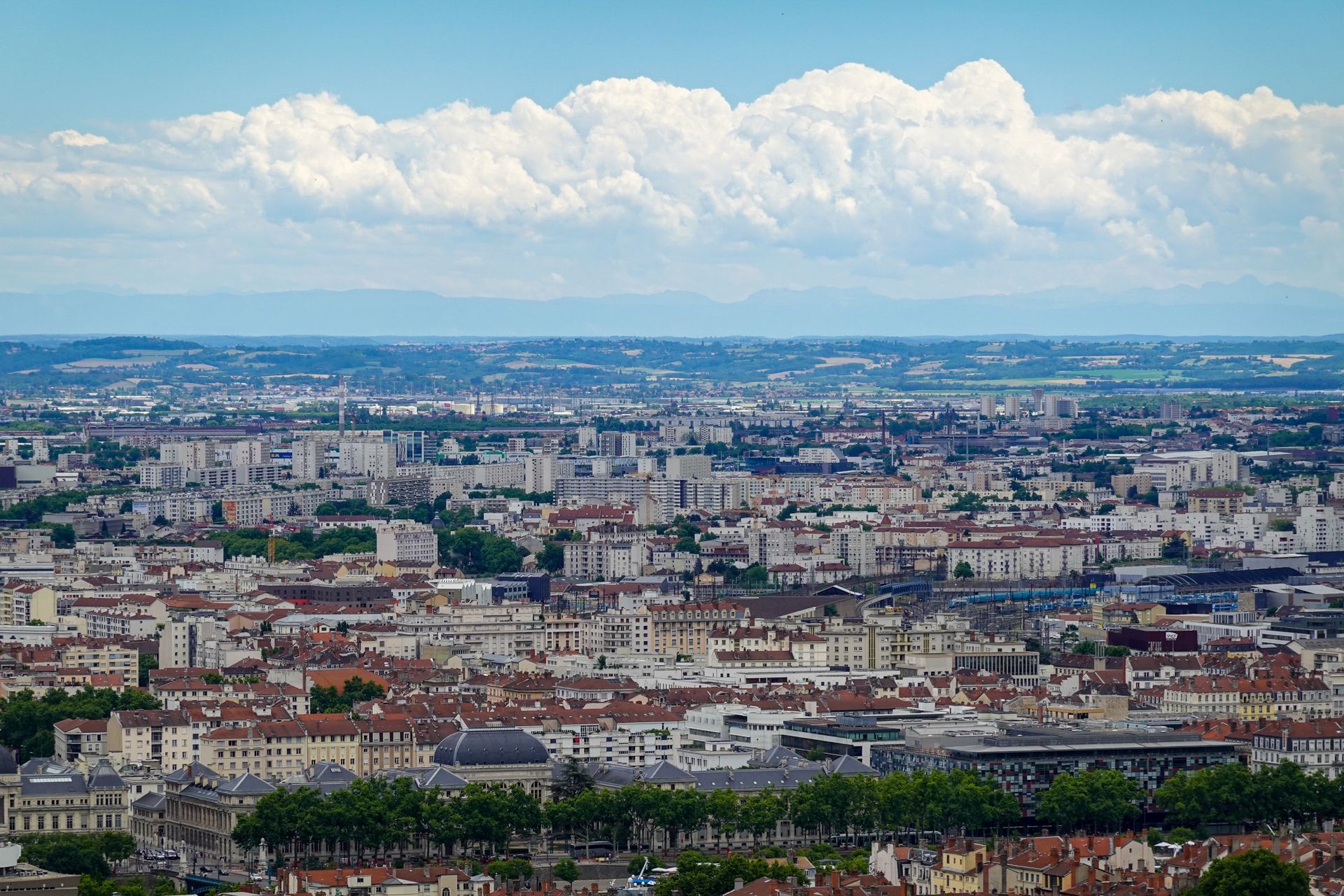 Aerial view of Lyon showcasing the sprawling urban landscape under a vibrant blue sky.