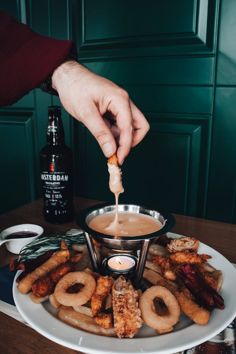 Person Dipping Food In Sauce