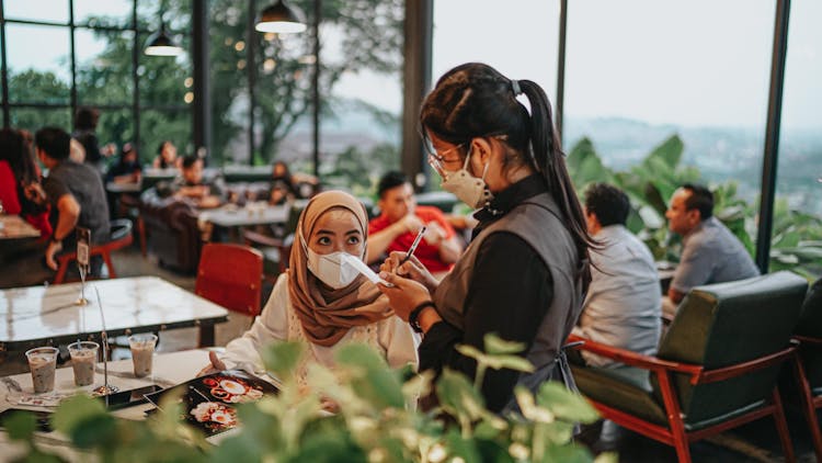 A Woman In Brown Hijab Ordering Food In The Restaurant