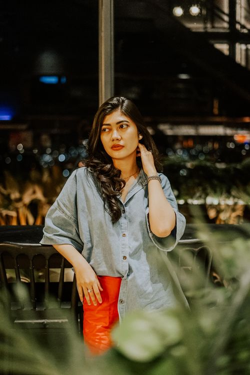 Free Asian woman with black hair and denim shirt posing indoors at night. Stock Photo