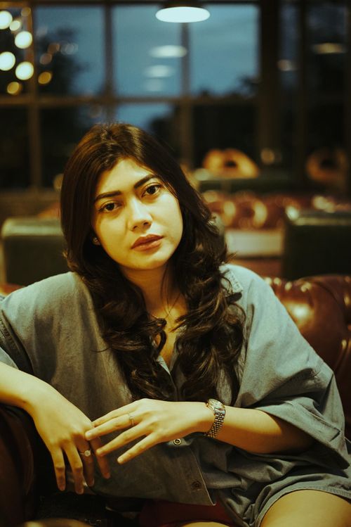 Free Portrait of a thoughtful Asian woman in a cozy indoor setting, wearing a casual blue shirt. Stock Photo