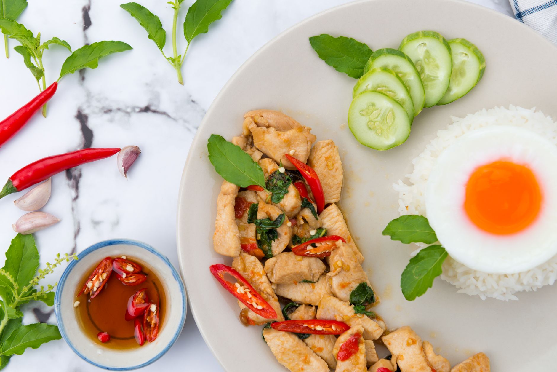 Bowl of mild Thai green curry with chicken, eggplant, and bell peppers in creamy coconut sauce, garnished with fresh Thai basil leaves