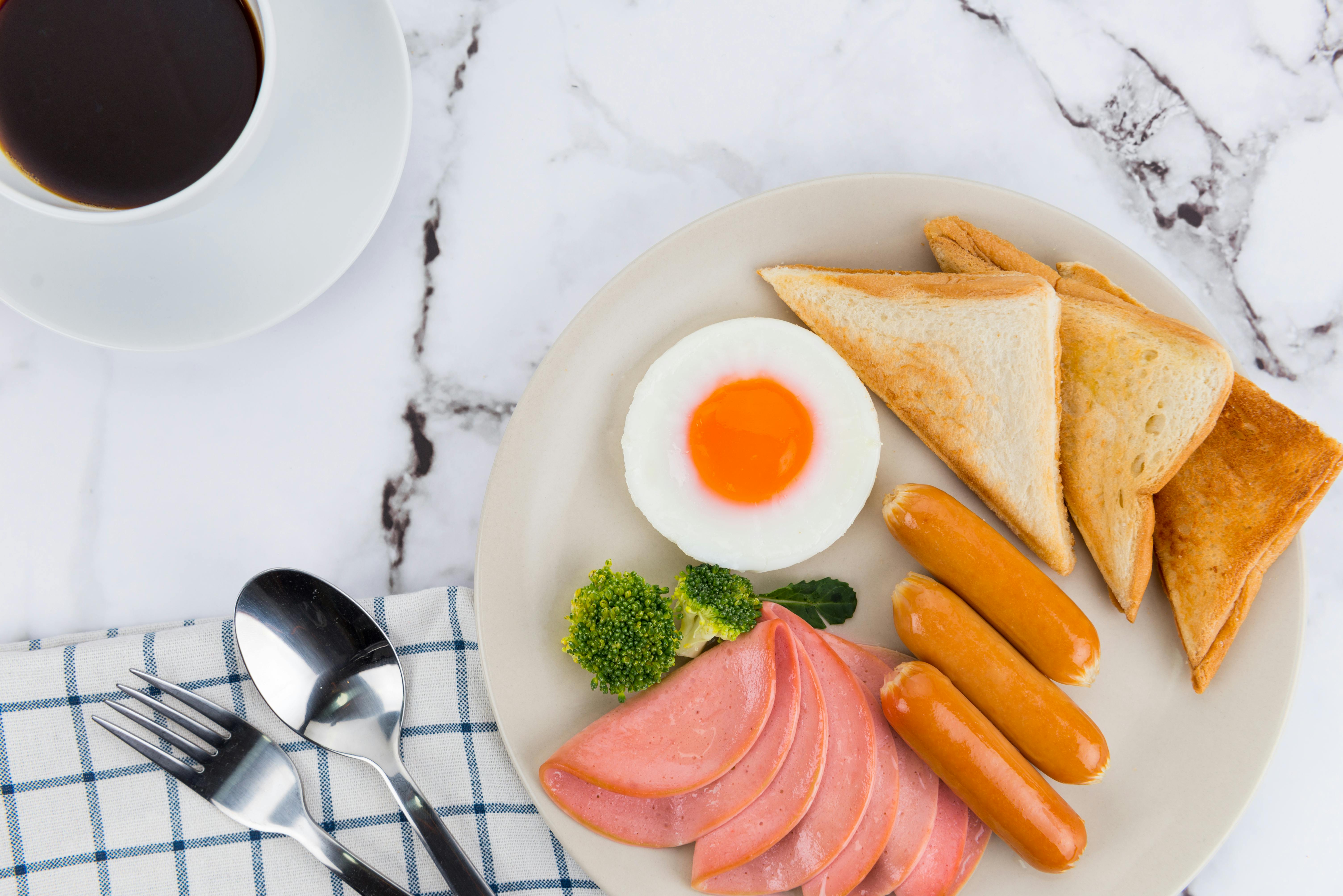 Traditional kaya toast breakfast set with soft-boiled eggs and kopi served on a marble kopitiam table in Singapore
