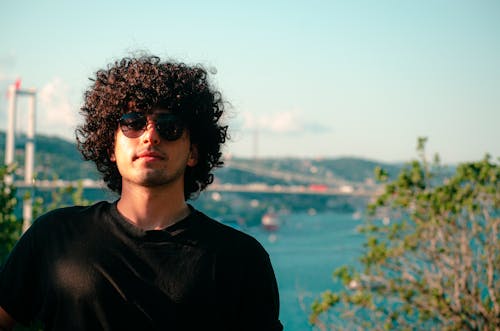 Man with Curly Hair Wearing Sunglasses and Black T Shirt