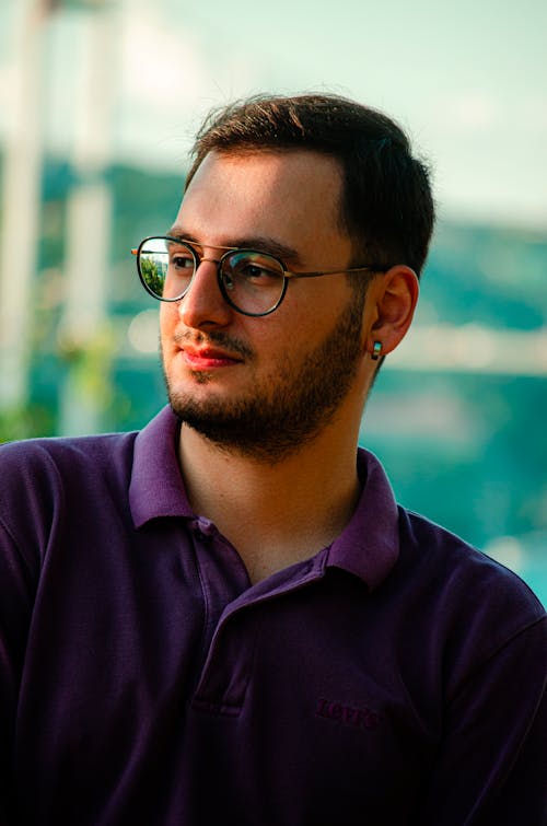 Man in Purple Polo Shirt Wearing Black Framed Eyeglasses while Looking Afar