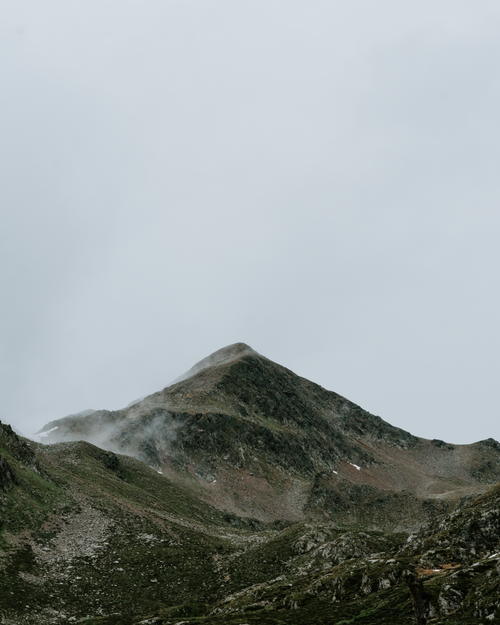Free Serene mountain peaks shrouded in fog and mist under a cloudy sky. Stock Photo