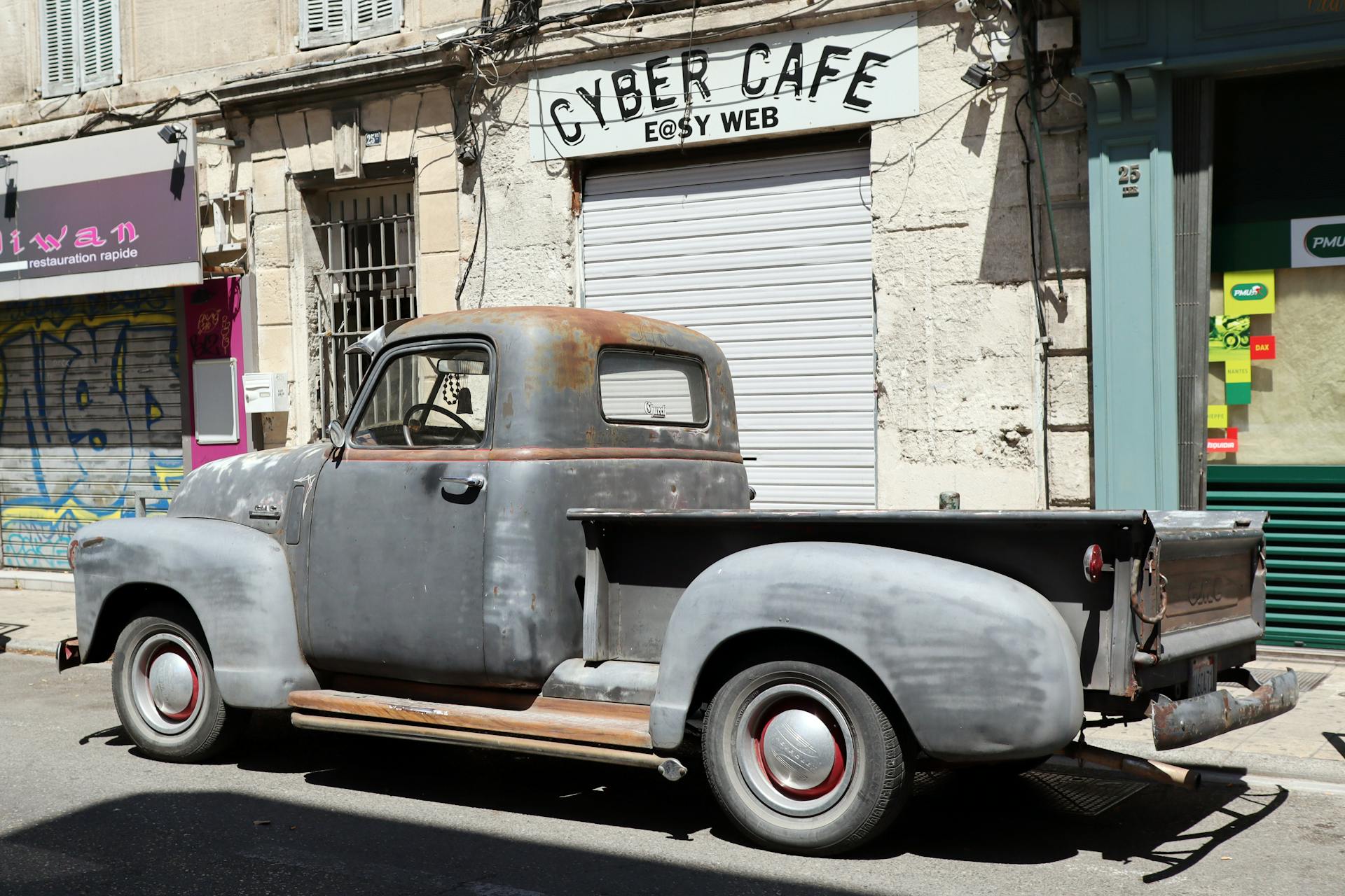 A retro Chevrolet pickup truck parked near a cyber cafe in Avignon, France.