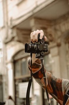 Close-up of a hand holding a DSLR camera in an urban setting. Perfect for travel and photography themes.