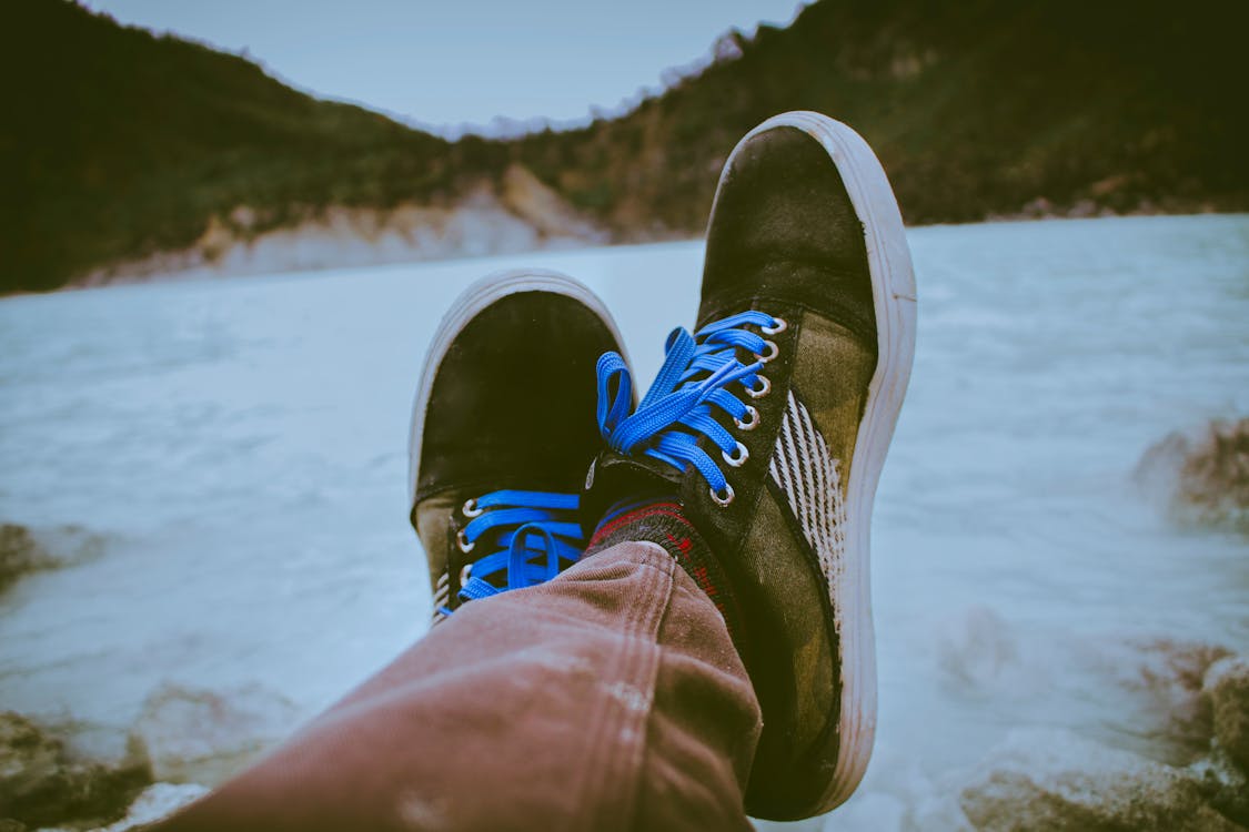 Free Person Wearing Black and Brown Shoes in Front of Body of Water Stock Photo