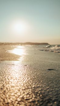 Peaceful beach scene at sunset with golden light reflections on wet sand.