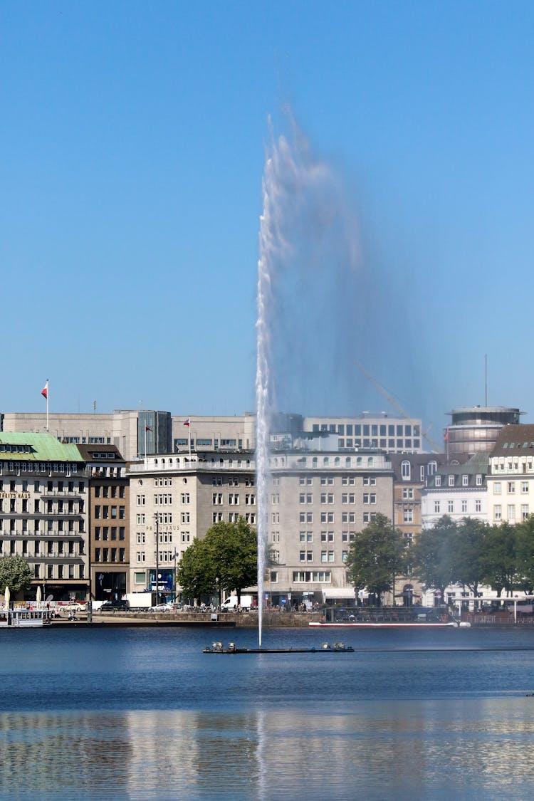 City Buildings Near Water Fountain On A Lake