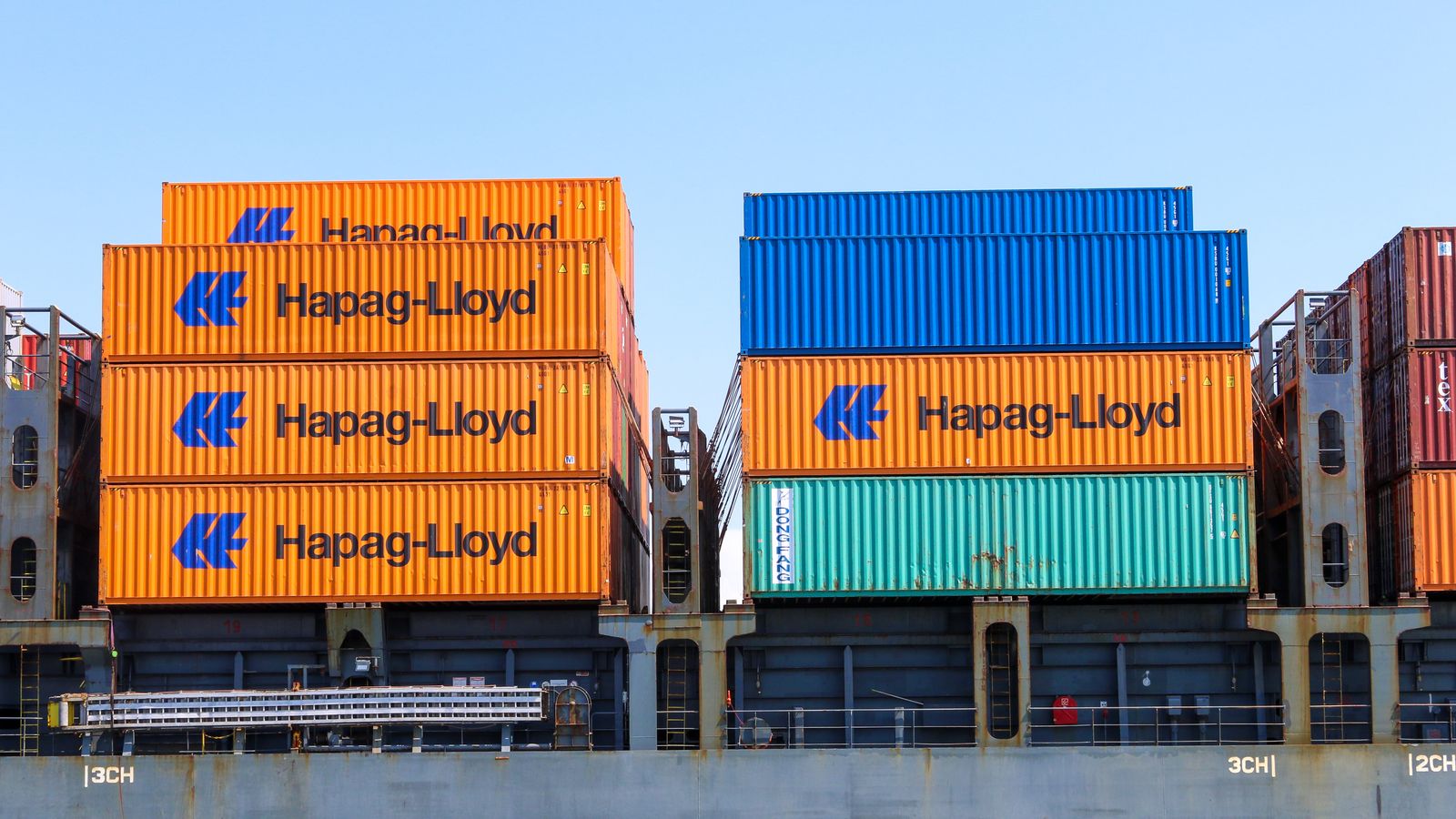 Colorful cargo containers stacked at an industrial port terminal.