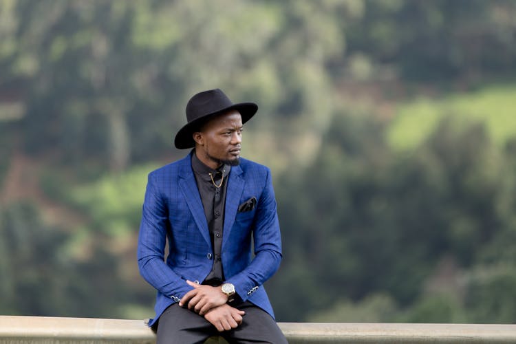 A Man In Blue Suit Jacket Wearing A Black Hat