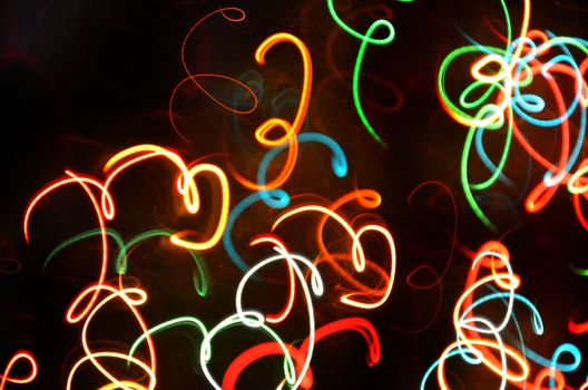 Colorful neon light swirls creating an abstract and dynamic pattern on a dark background.