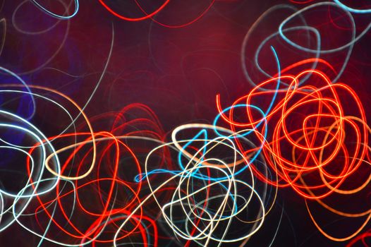 Dynamic neon light trails in red, blue, and white swirl on a dark canvas, creating an abstract visual art piece.