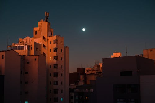 View of Full Moon Above Concrete Buildings during Night Time