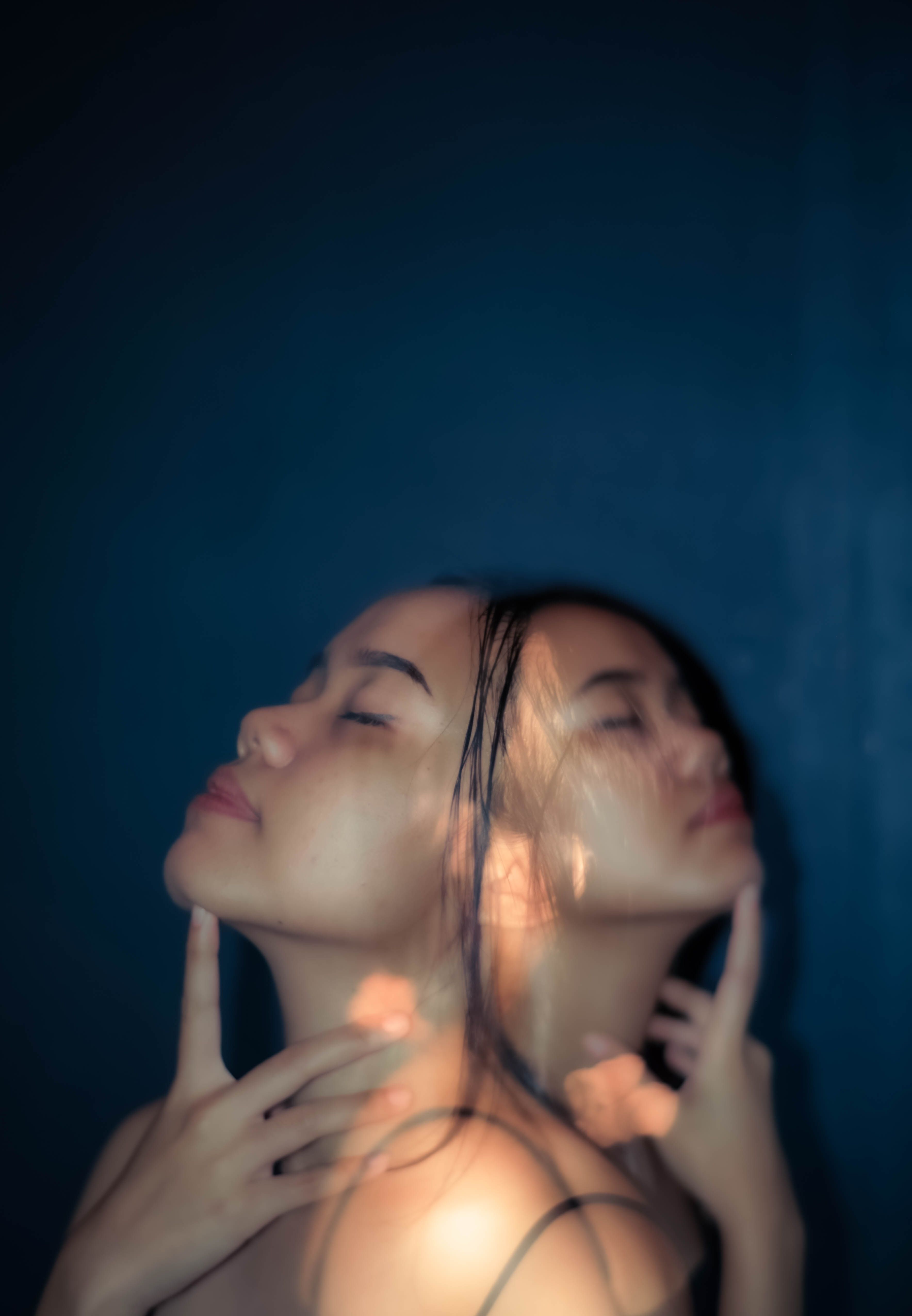 A young woman with a double exposure effect on a blue background showcasing a creative and artistic style.