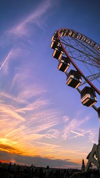 Capture of a Ferris wheel silhouetted against a colorful sunset sky during twilight, offering a dreamy and vibrant scene.