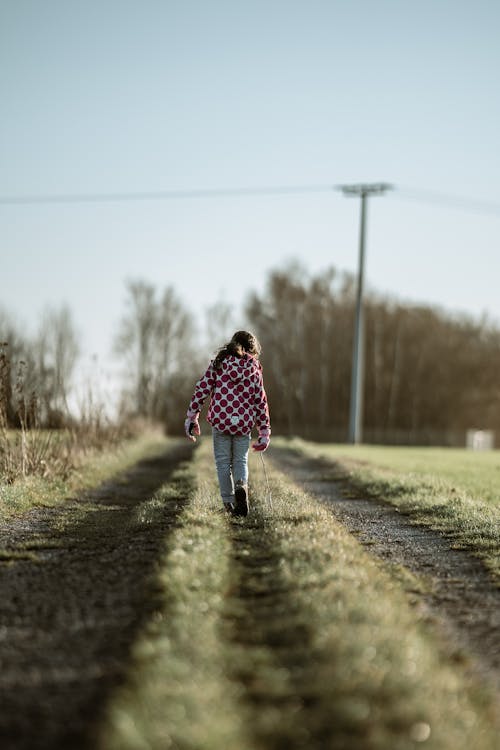 Back View Shot of a Girl Walking on a Grassy Ground