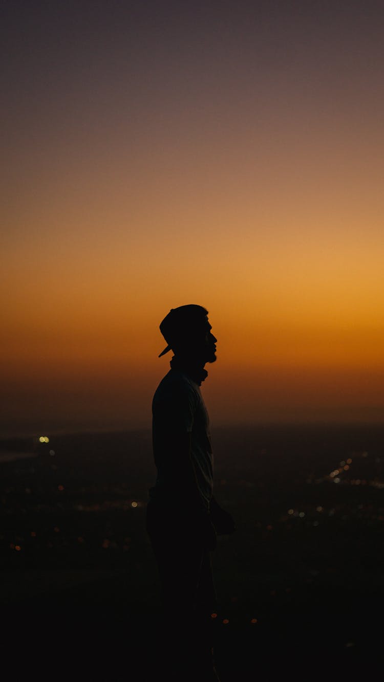 Silhouette Of A Man In A Cap With Sunset As The Background