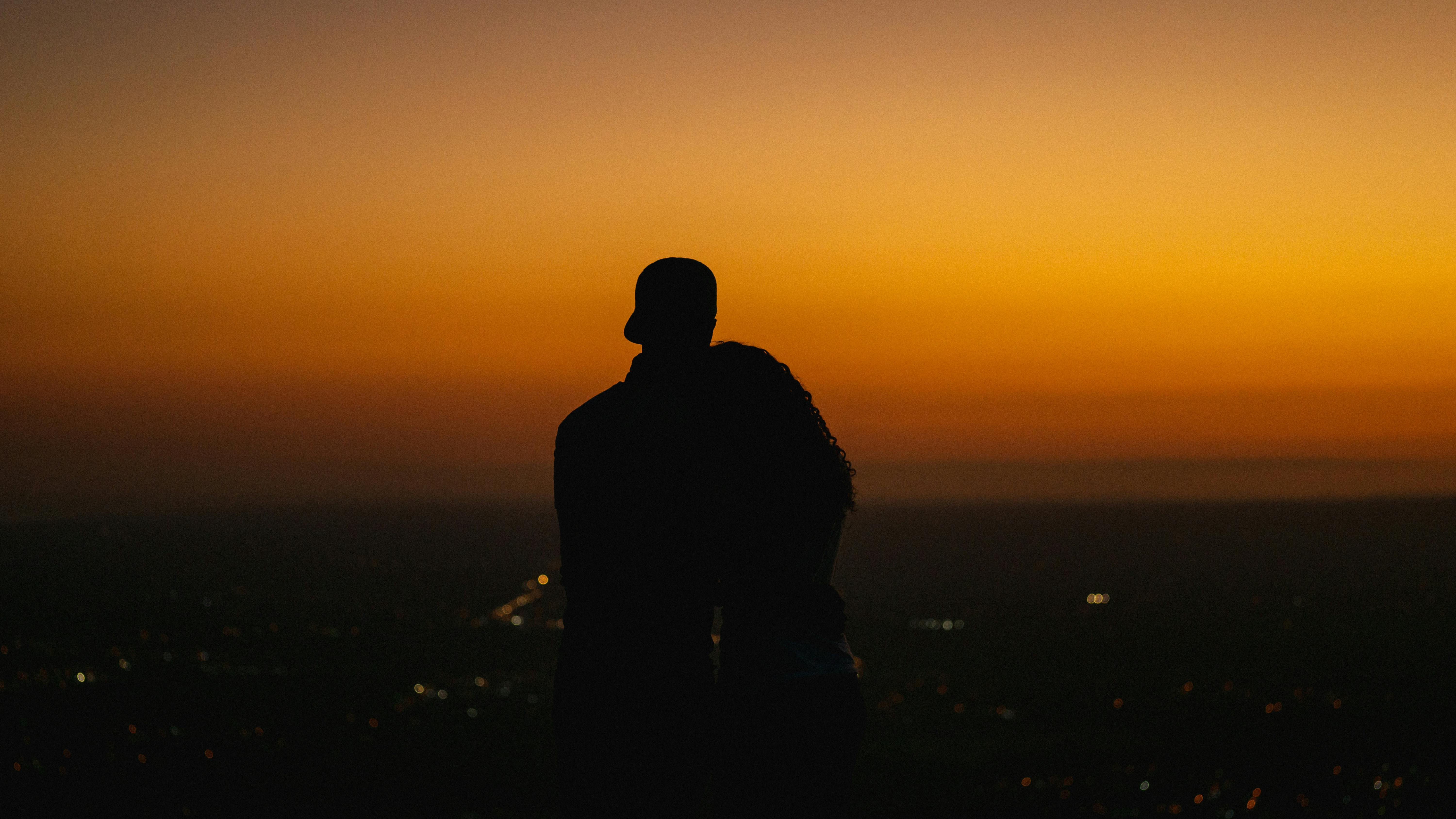 Embracing couple silhouetted against a vibrant sunset in Panama City, Panama.