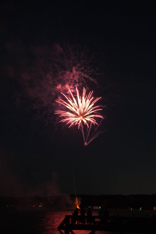 Free Fireworks illuminate the night sky over a dock in Conway, AR, creating a stunning display. Stock Photo