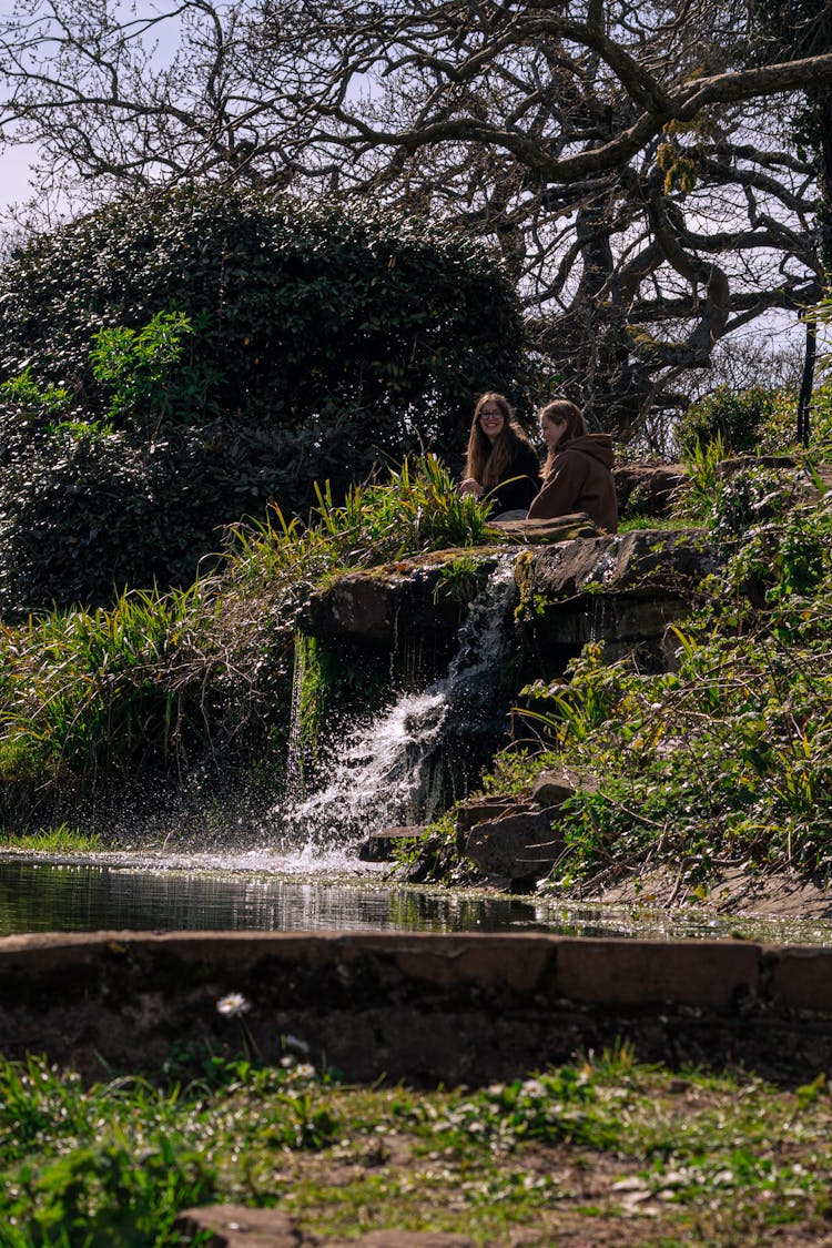 Friends Sitting Near A Waterfall