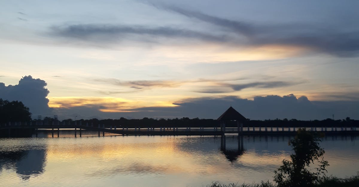 Peaceful sunset view over a lake with a pier in Mueang Tai, Thailand.