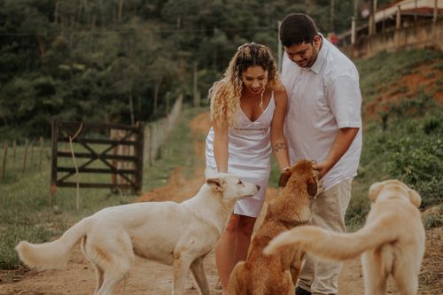Free A couple in white outfits interacts with dogs on a rural path in Teófilo Otoni, capturing a joyful moment. Stock Photo