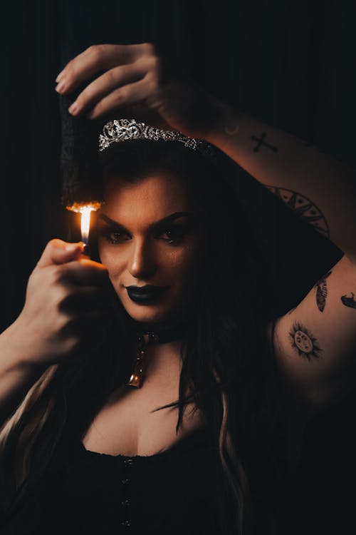 Tattooed Woman Setting a Piece of Wood on Fire