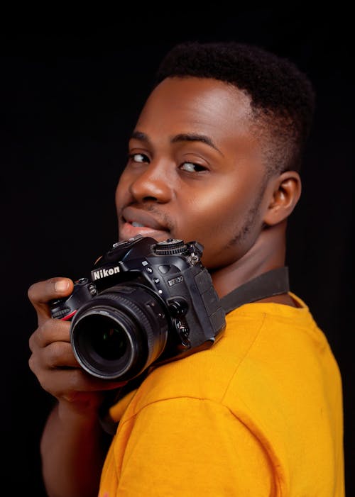 Foto profissional grátis de cabelo afro, câmera dslr, camisa amarela