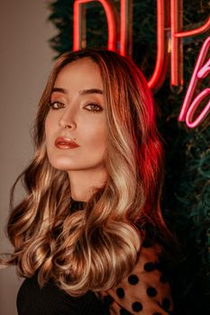 Elegant woman with wavy hair and red neon accents, exuding modern style.
