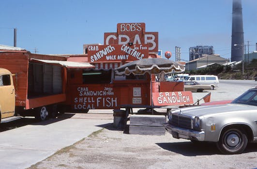 Retro food truck selling crab sandwiches in an industrial area on a sunny day.