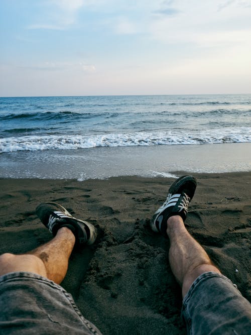 Free Person in Black and White Nike Sneakers Sitting on Beach Shore Stock Photo