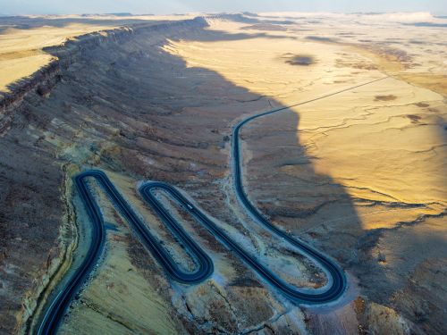 Free Stunning aerial view of a zigzag road across the barren landscape of Mitzpe Ramon. Stock Photo