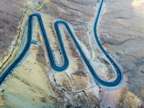 Free Scenic aerial view of a zigzag road cutting through the arid landscape of Mitzpe Ramon, Israel. Stock Photo