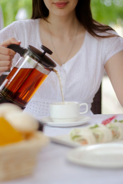 Woman Pouring Tea in a Cup