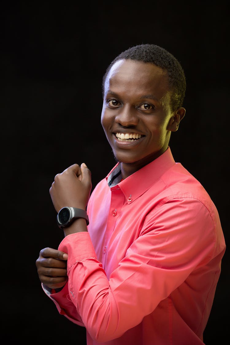 Photo Of Smiling Man Closing A Cuff Of A Red Shirt And Wearing Watch On His Hand