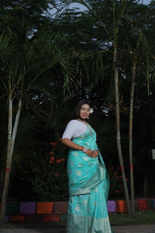 Woman in Turquoise Sari Standing under Palm Trees