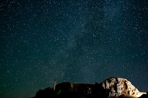 Free Person Standing on Rock Formation Under Starry Night Stock Photo