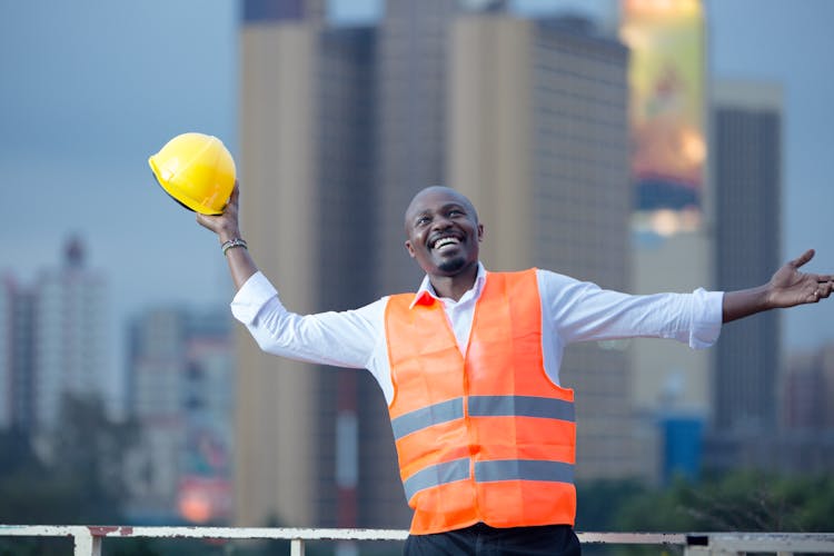 Smiling Man Holding Yellow Safety Helmet In Hand