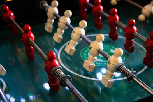 Close-up of red and white foosball players on a classic game table.
