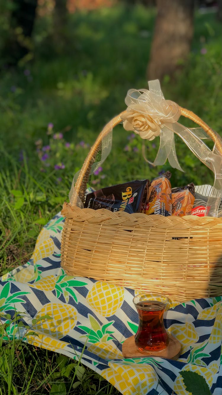 Wrapped Food In A Brown Woven Basket On A Picnic Blanket