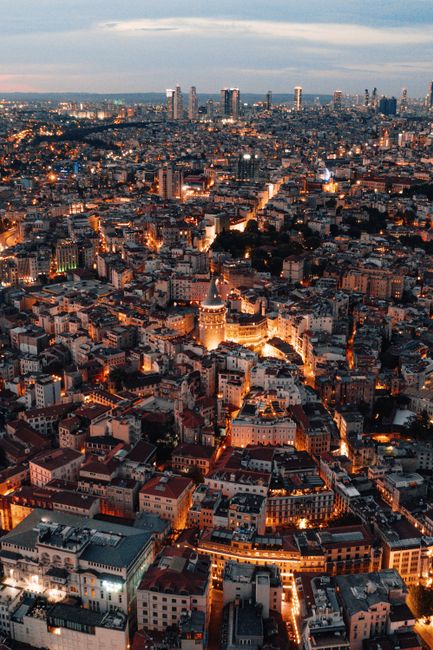Captivating aerial view of illuminated Istanbul cityscape featuring Galata Tower at twilight.