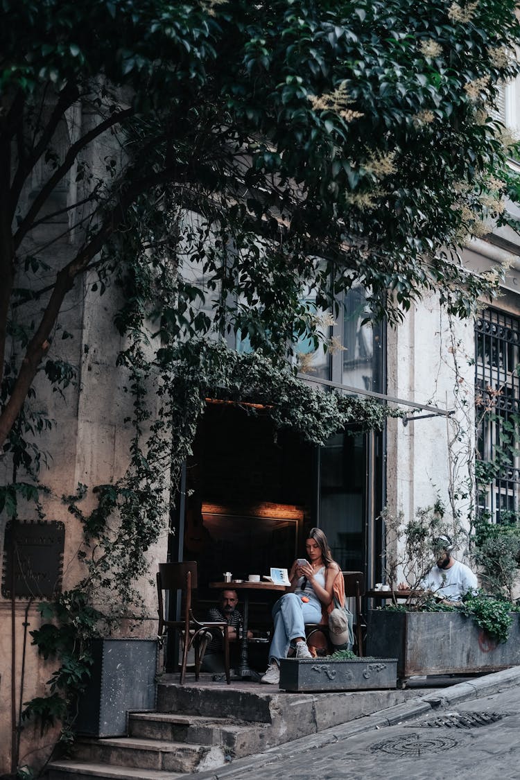 Woman Sitting Outside Of Cafe In Town