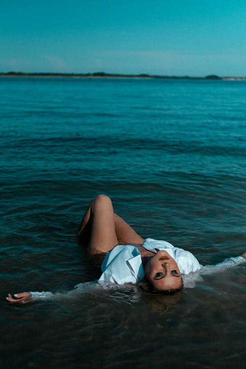 A Woman in White Long Sleeves Lying on the Beach