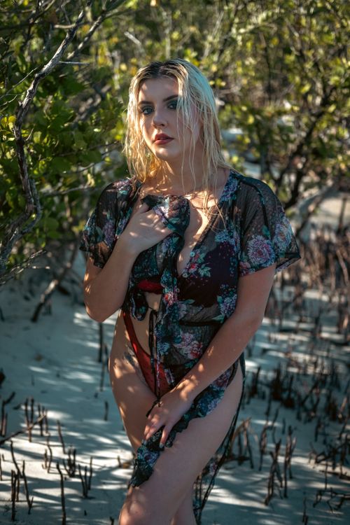 Free A young woman in floral swimwear poses stylishly on a sunny beach. Stock Photo