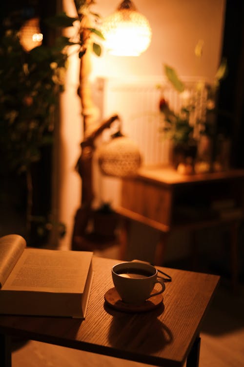 A Cup of Coffee Near the Book on a Wooden Table