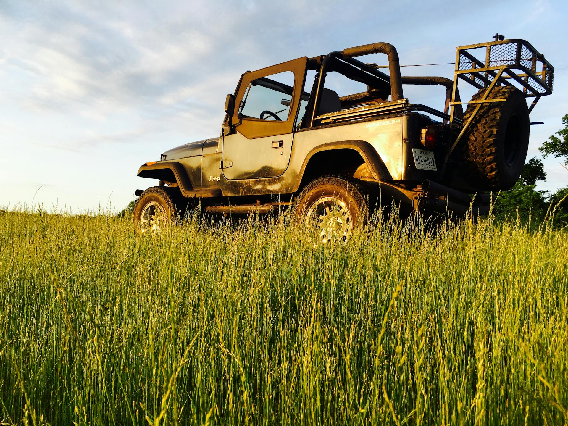 Rugged jeep parked on a grassy field in Caddo Mills, TX during sunset. Ideal for adventure and off-road themes.